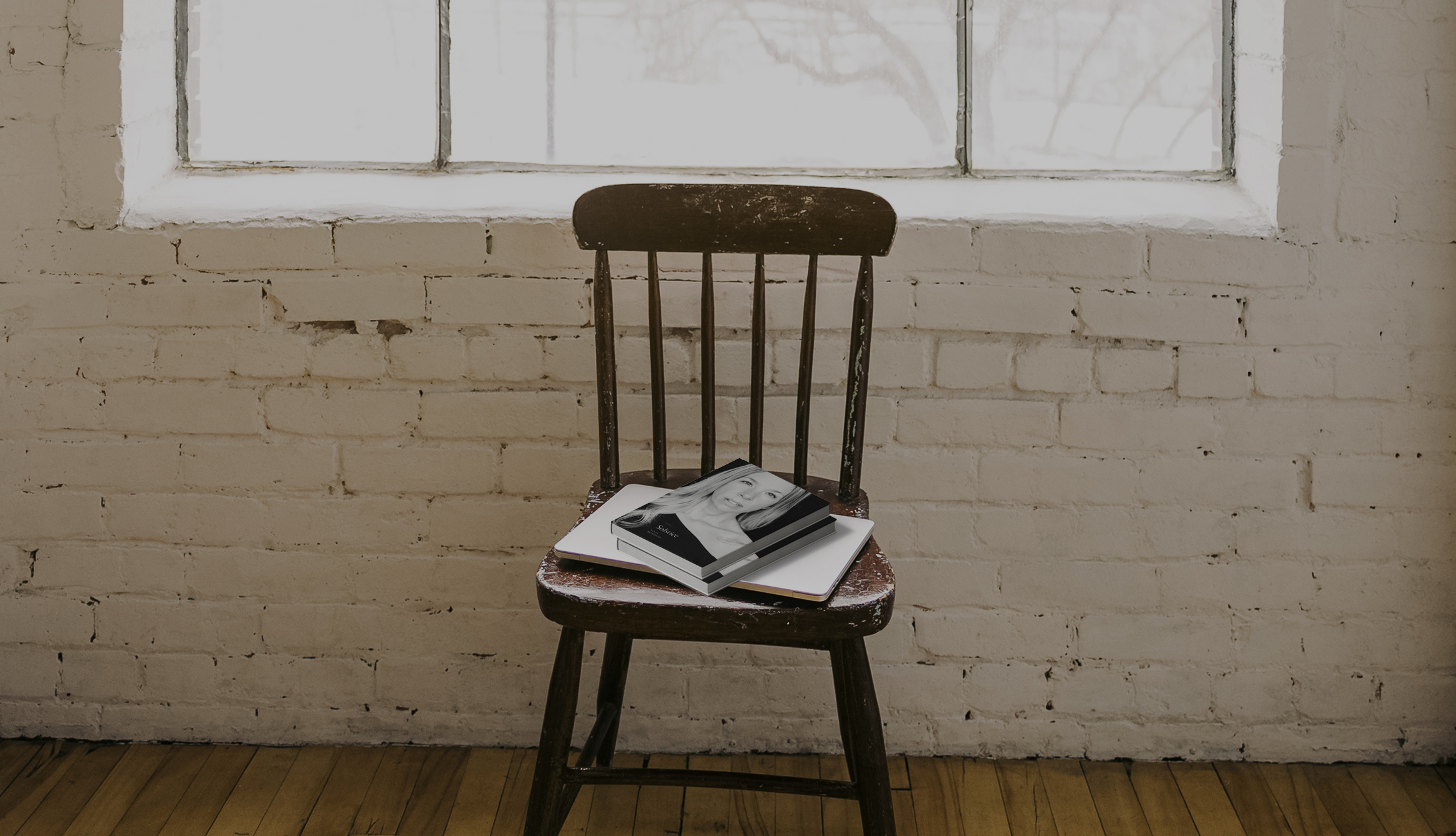 Solstice book on a chair and white brick wall with a window